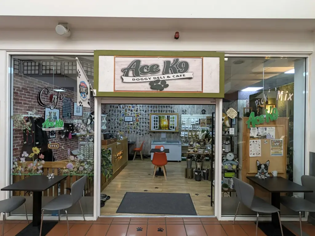Front of Ace K9 Doggy Deli and Cafe in Maylord Orchards, Hereford, with tables outside and treats on the shelves inside